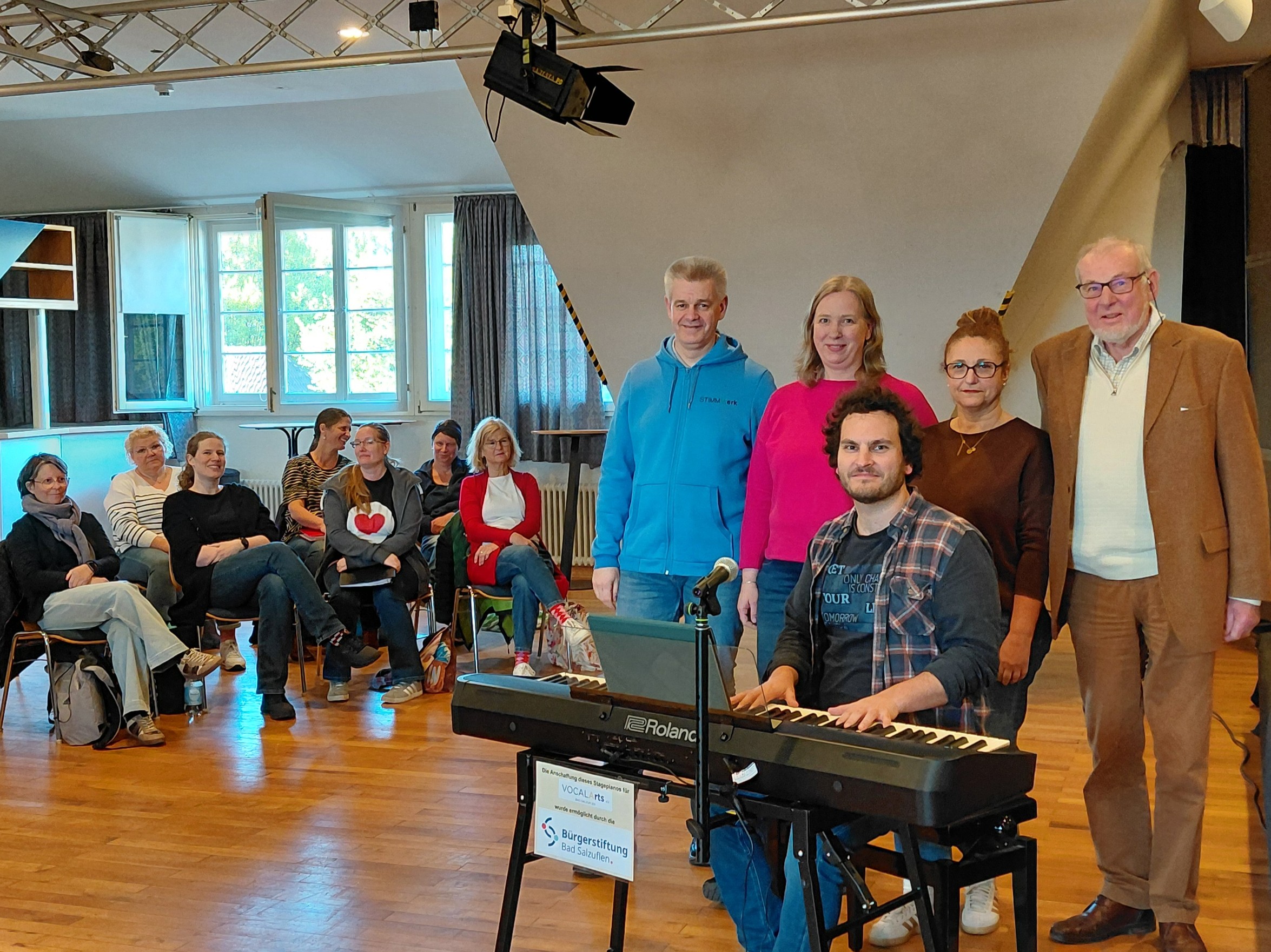 Bei einer Probe des gemischten Chores STIMMWerk in der Gelben Schule zeigte sich Udo Voßhenrich, Vorstandsvorsitzender der Bürgerstiftung Bad Salzuflen (rechts), begeistert vom Engagement der Mitglieder des Chorvereins VOCALArts e.V. (von links im Vordergrund): Klaus Lüttgens (Leiter Finanzen), Marion Schuler (Leiterin Verwaltung), Simon Becking (Chorleiter) und Victoria Jimenez (Leiterin Marketing-Mix) sowie im Hintergrund weitere Mitglieder des Chores. Foto: VOCALArts e.V., Rainer Neuhaus.