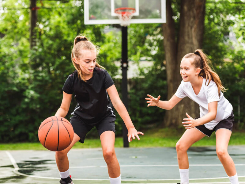 Zwei jugendliche Mädchen spielen Basketball im Freien