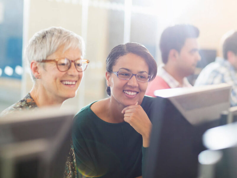 Eine ältere und eine jüngere Dame vor einem Computerbildschirm