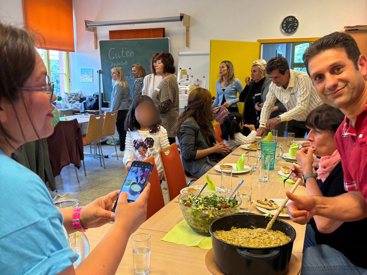 Erwachsende und Kinder um einen Tisch mit gefüllten Tellern darauf